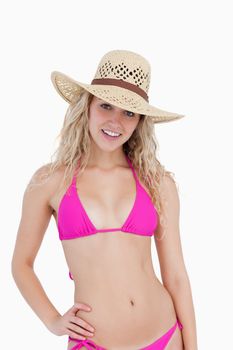 Smiling teenager wearing a pink swimsuit and a hat against a white background