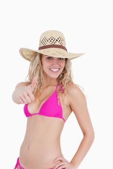 Thin teenager in beachwear showing her thumbs up against a white background