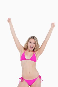 Young attractive woman in beachwear raising her arms against a white background