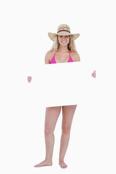 Smiling teenager in a pink swimsuit holding a blank poster against a white background