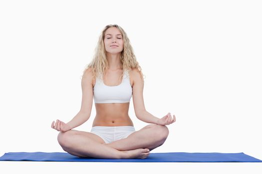 Young attractive woman doing yoga in sportswear against a white background