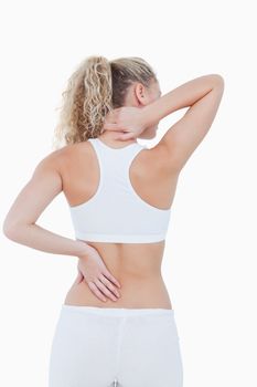 Blonde woman showing pain in her back and in her neck against a white background