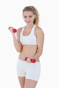 Young smiling woman lifting weights against a white background