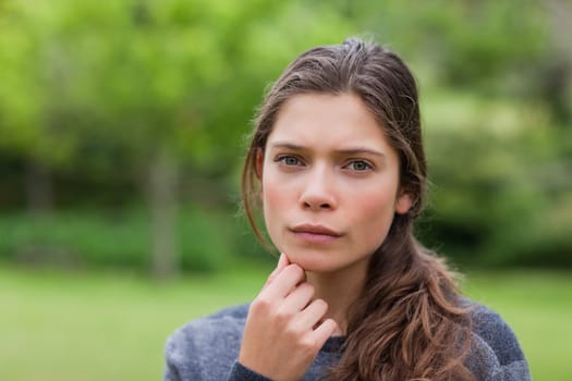 Young thoughtful adult looking at the camera while placing her hand on chin