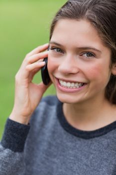 Teenage girl talking with her cellphone while looking straight at the camera