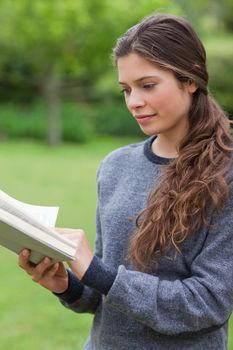 Young relaxed woman reading a book while standing upright in the countryside