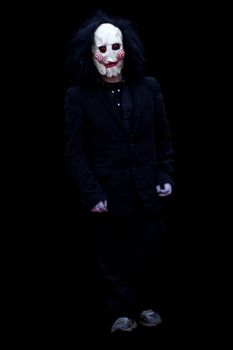 Black devil man standing  and wearing a black suit isolated on black background.