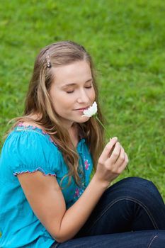 Young relaxed girl smelling a beautiful white flower while closing her eyes