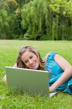 Young woman showing a great smile while lying on the side and using her laptop