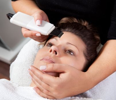 Young woman receiving laser therapy. Spa studio shot