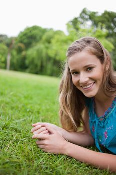 Young attractive woman lying down on the grass in a parkland while smiling