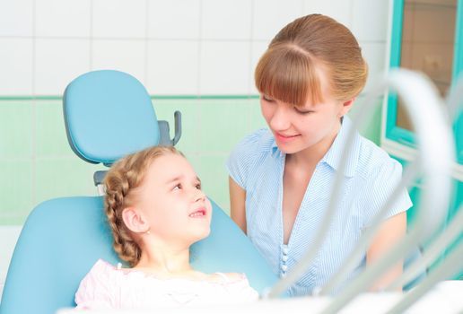 mother and daughter visit the dentist, the child is sitting in the dental chair and mother near