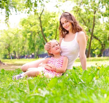 mother and daughter sitting together on the grass, and spend time with family