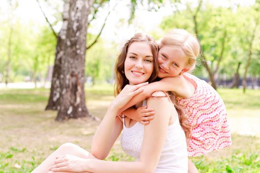 mother and daughter sitting together on the grass, and spend time with family