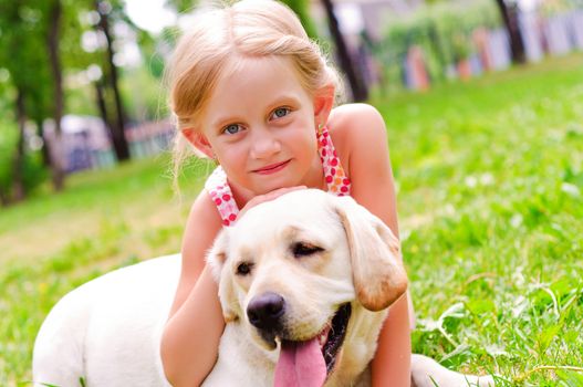 girl and she lablador, hugging in the park lying on the grass