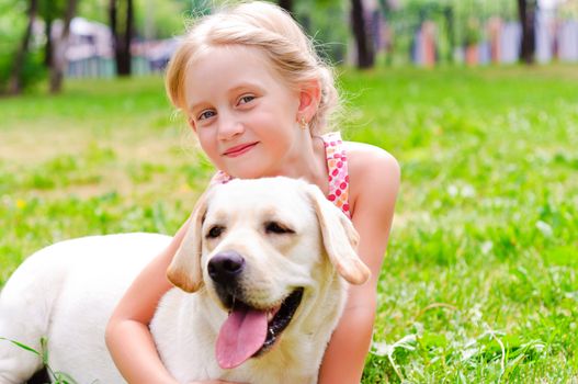 girl and she lablador, hugging in the park lying on the grass