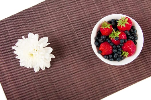 strawberries, bilberry and flower on bamboo tablecloth, still life