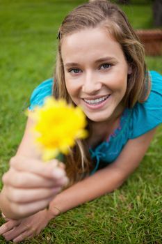 Smiling student holding a beautiful yellow flower while looking straight at the camera