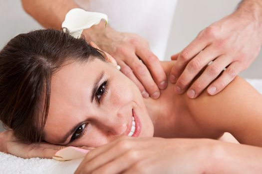 Beautiful young woman getting shoulder massage at spa