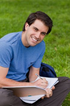 Young man sitting cross-legged while beaming and working with his notebook