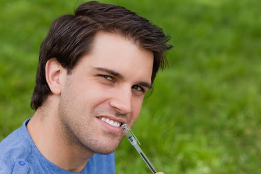 Young thoughtful man looking straight at the camera while holding his ballpoint pen