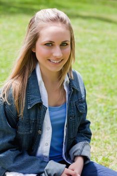 Young attractive blonde girl sitting on the grass in the countryside