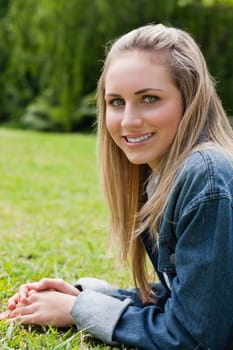 Young attractive girl looking at the camera while lying on the grass in a public garden