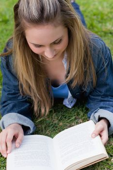 Young relaxed girl lying on the grass in the countryside while reading a book