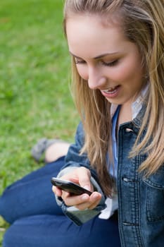 Attractive blonde teenage girl receiving a surprising text while sitting in a park