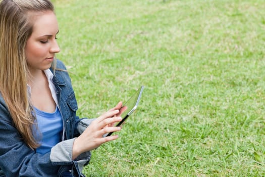 Young serious girl using her tablet computer in a public garden