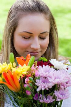 Young peaceful girl closing her eyes while smelling a beautiful bunch of flowers
