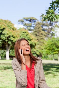 Woman laughing on the phone while looking into the sky with the sun shining on her face
