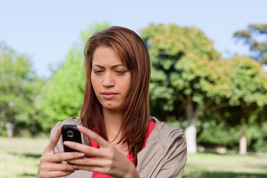 Woman curiously reading a text message in a sunny park area