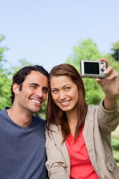 Woman and her friend looking towards her camera for a picture of them to be taken in a grassland area