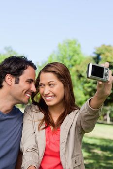 Young woman and her friend look at each other while she takes a photo of them together using her camera