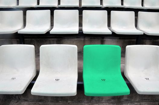 A single green chair in a multitude of white chair