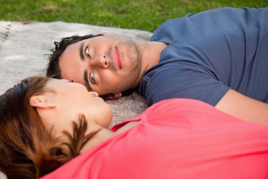 Man looking into his female friends eyes while lying on a grey quilt