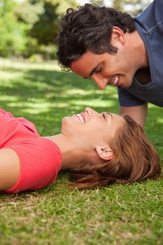 Man smiling as he looks down into the eyes of his friend who is lying on the grass