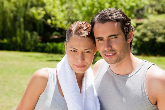 Woman with a white towel around her neck standing with a smiling man in workout gear