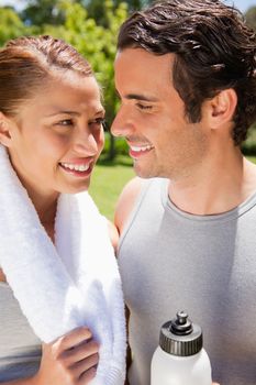 Smiling woman holding a white towel while looking at a man who is holding a white sports bottle