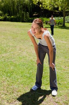Woman smiling as she bends over recovering while a man is walking towards her in the background