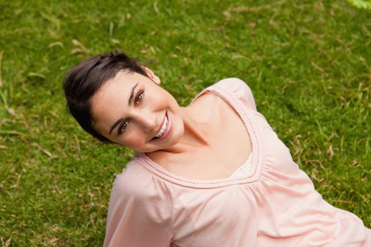 Smiling woman with her head tilted to one side while lying down on grass