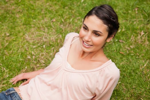 Woman smiling and looking straight ahead as she lies down on the grass