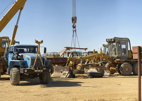 Repair road grader in the field, crane holding the front foot.