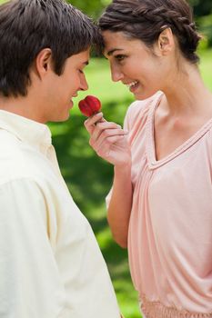 Man being offered a strawberry by his smiling female friend in a park