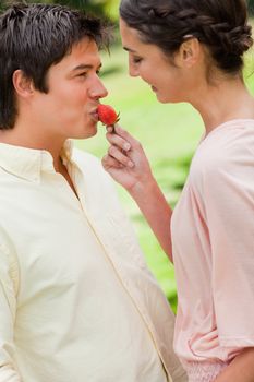 Woman smiles as she feeds her friend a strawberry in a park