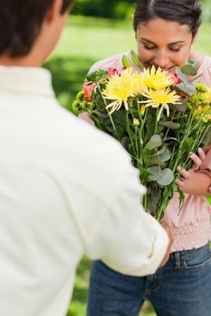 Woman smelling the bouquet of aromatic flowers which has been presented to her by a friend 