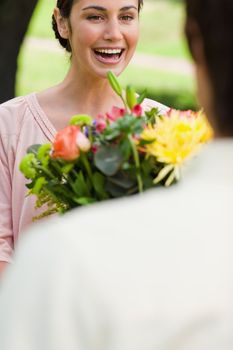 Woman laughing enthusiastically as she is given a bouquet of flowers by her friend 