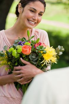 Woman smiling as she holds flowers which have been given to her by a friend 