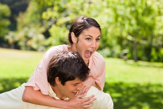 Woman laughing as her friend is carrying her on his back